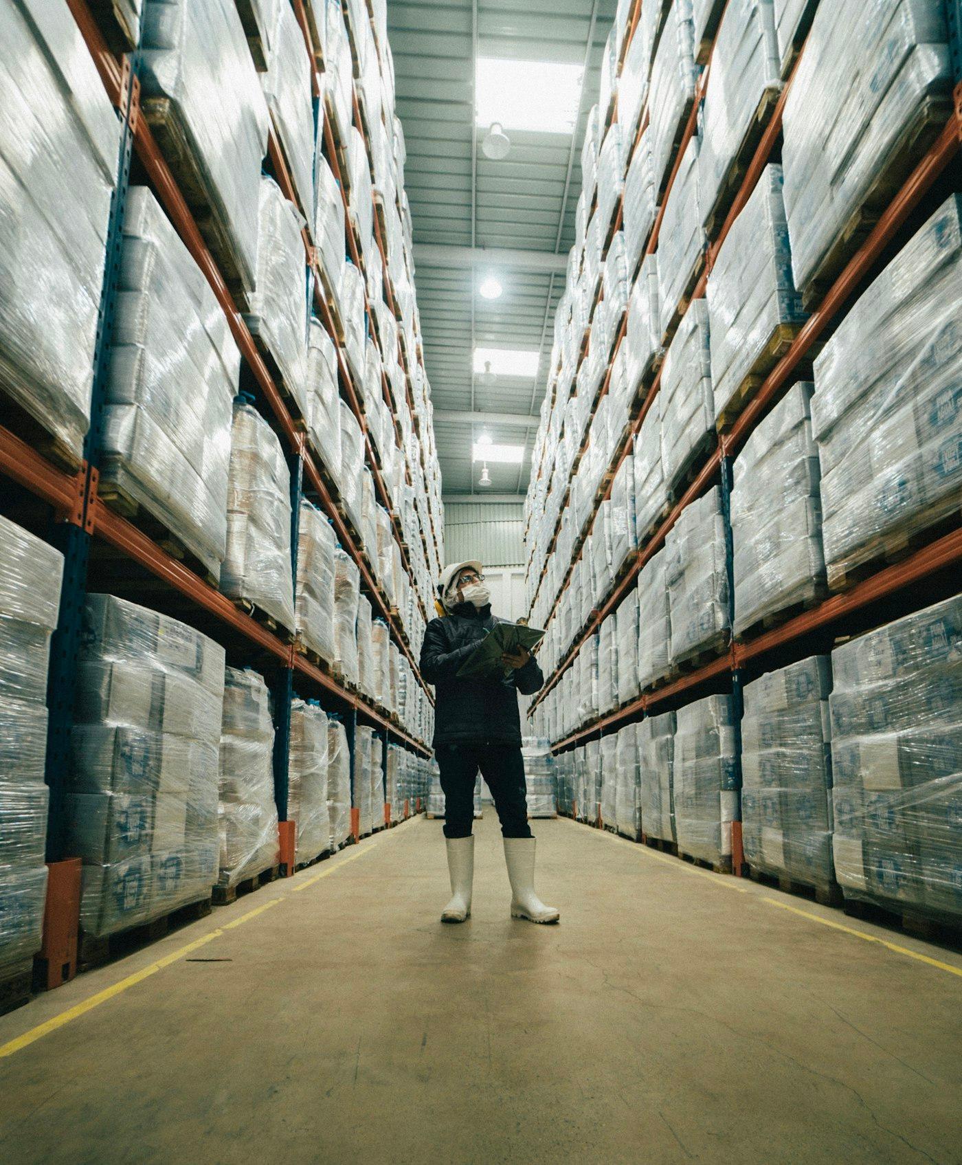 A single worker checking stock against a list in a warehouse aisle